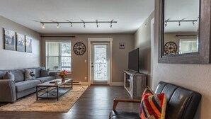 A living room with a sofa, coffee table, TV, and a mirror. - The Peachtree Paradise: Hot Tub, Free Shuttle (Crested Butte)