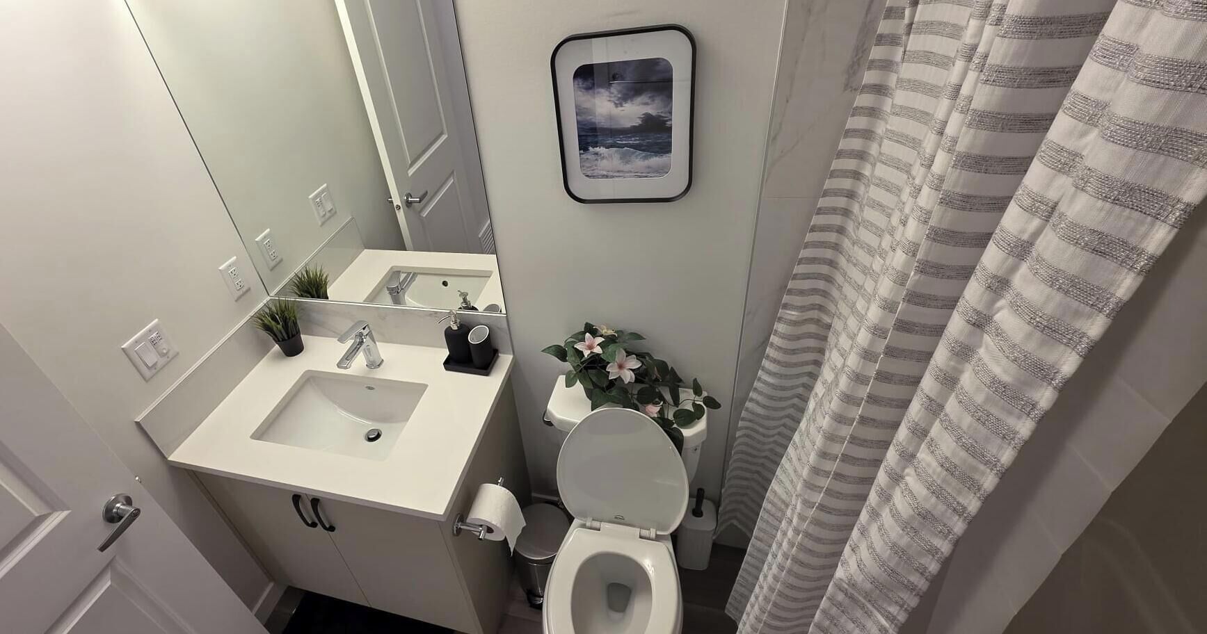 A bathroom with a sink, toilet, and shower curtain.