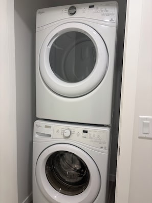 A stacked washer and dryer unit in a laundry room. - CobbleBrook Executive Suites; family Friendly (Airdrie)