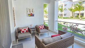 Ein modernes Wohnzimmer mit Deckenventilator, einer Sofagarnitur, einem kleinen Tisch und einem Gemälde an der Wand.