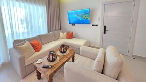 Ein modernes Wohnzimmer mit einer Couch, einem Couchtisch und einem an der Wand befestigten Fernseher.