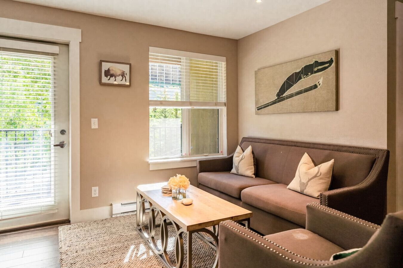 Een woonkamer met een bank, een bijzettafeltje en een schilderij aan de muur.