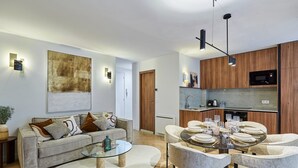 Un soggiorno moderno con un divano, un tavolino da caffè e un'area pranzo con sedie e tavolo apparecchiato per un pasto.