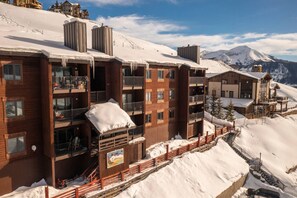 Un hôtel à plusieurs étages doté de balcons, d’un télésiège et situé dans un cadre montagneux.