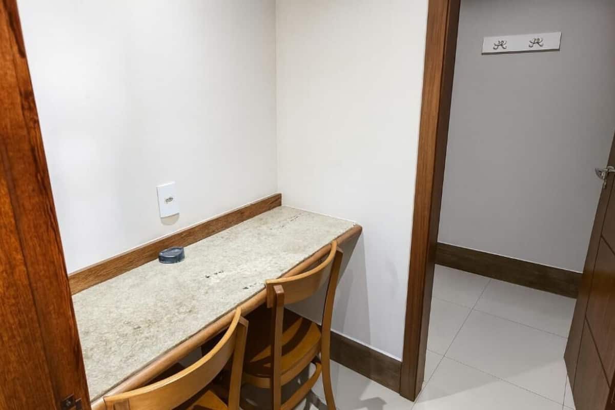 A small room with a wooden table and chairs, a white wall, and a door with a nameplate.
