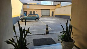 Un espace de stationnement avec une voiture, un cône et des plantes en pot.