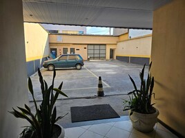 A parking area with a car, a cone, and potted plants.