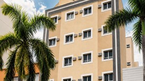Un hôtel à plusieurs étages, doté d’une façade sobre, de climatiseurs et d’une grande enseigne indiquant « À l’aide ! ».