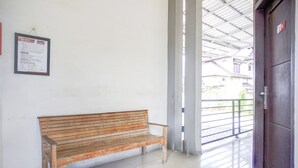 A wooden bench in a hallway with a sign on the wall and a door leading outside.