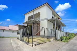 A two-story house with a covered porch, a gated entrance, and a visible staircase leading to the upper floor.