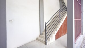A staircase with a metal handrail, white walls, and a red gate.