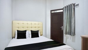 A bed with a tufted headboard, a dark-colored bedspread, and two pillows.