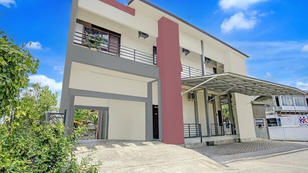 A modern building with a flat roof, a central vertical red structure, and a covered entrance area.