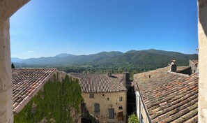 Une vue sur un paysage montagneux, avec des bâtiments traditionnels en pierre et des toits en tuiles de terre cuite.