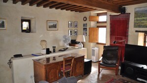 Un salon rustique avec un plafond en bois, une cheminée, un téléviseur, une table à manger et une chaise.