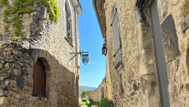 Une ruelle pavée bordée de bâtiments historiques en pierre, avec une enseigne indiquant l’emplacement d’un musée.