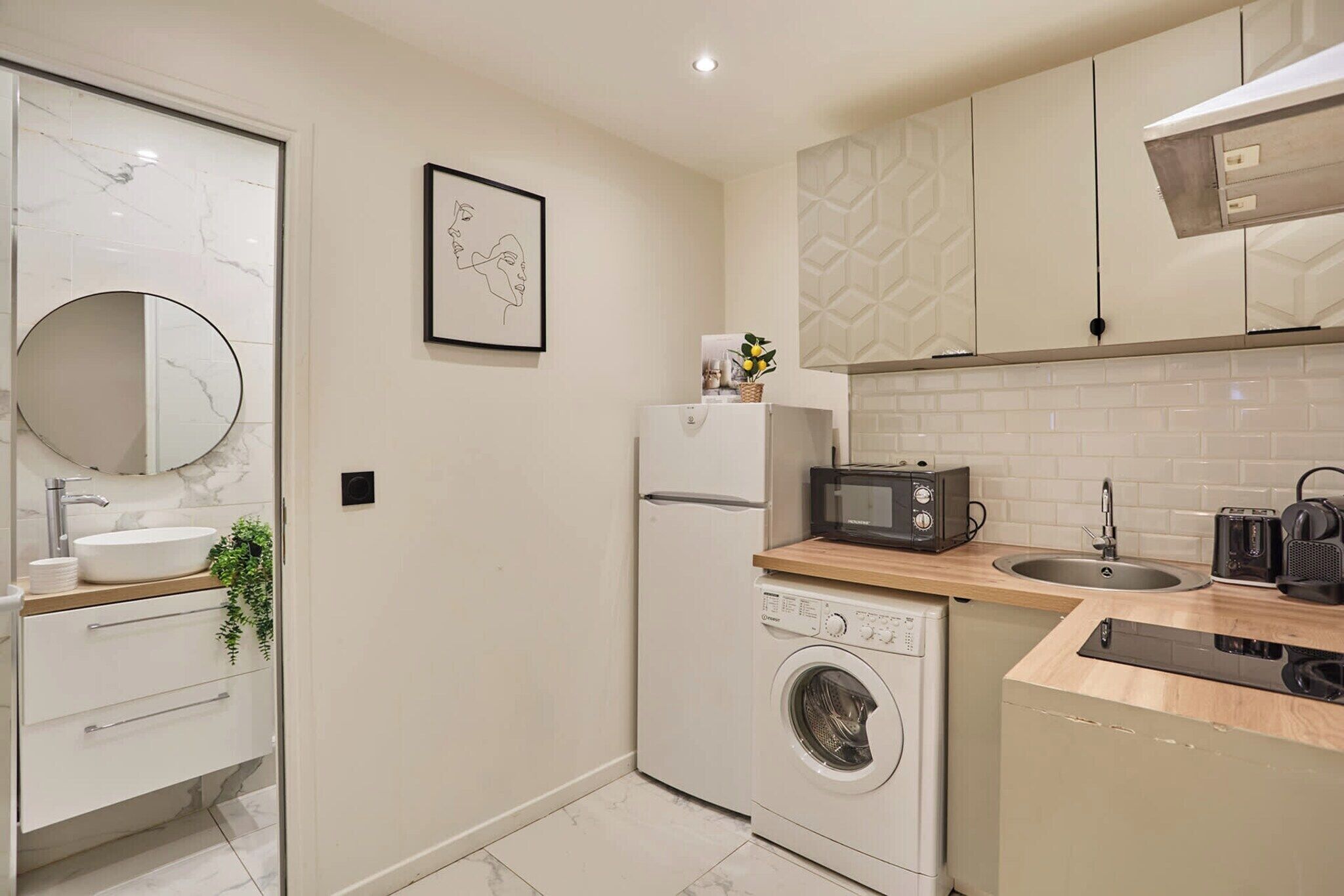 Une cuisine compacte équipée d’un lave-linge, d’un four à micro-ondes et d’un évier.