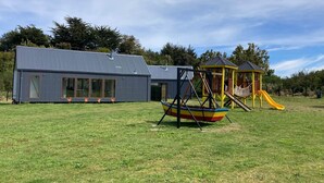 Ein modernes Gebäude mit großen Fenstern und einem Spielplatz mit Rutsche.