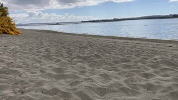 A sandy beach with a calm body of water and a distant shoreline.