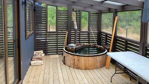 A wooden deck with a hot tub, a bench, and a wooden ladder. - Fully equipped cabin in Chiloé, steps from the beach (Ancud)