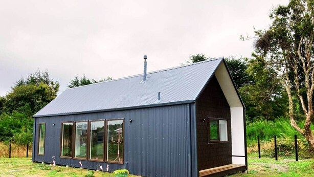A modern, single-story house with a sloped roof, large windows, and a small porch area. - Fully equipped cabin in Chiloé, steps from the beach (Ancud)