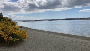 A beach with a sandy shore, a body of water, and a distant shoreline. - Fully equipped cabin in Chiloé, steps from the beach (Ancud)