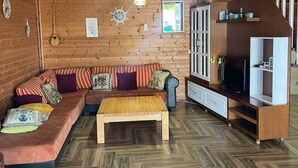 A cozy wooden interior with a sofa, television, and herringbone-patterned flooring. - A two-storey wooden villa fully equipped with all amenities with Love (Durrës)