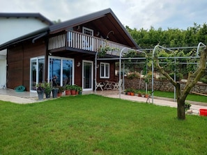A wooden house with a balcony, potted plants, and a garden.