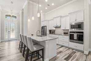 A modern kitchen with white cabinetry, a granite island, and stainless steel appliances. - Hernando Home with Screened Lanai, Near Springs (Hernando)