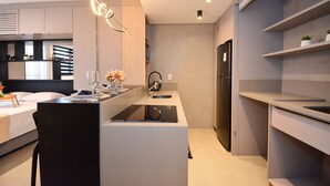 Una cocina moderna con una isla central, electrodomésticos integrados y un área de comedor con una silla y mesa.