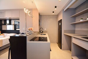 Una cocina moderna con una isla central, electrodomésticos integrados y un área de comedor con una silla y mesa.