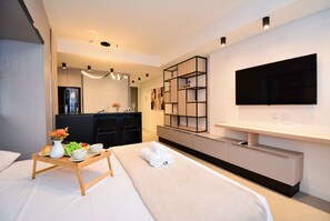 Una habitación de hotel moderna con cama, mesita de noche, televisor y estanterías empotradas.