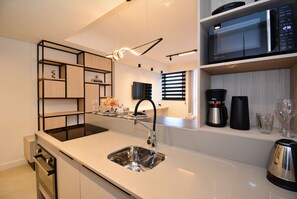 Una cocina moderna con un lavamanos de acero inoxidable, un microondas y una cafetera sobre la encimera.