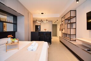 A modern hotel room with a bed, bedside table, and a small kitchenette. - Studio em frente a UFSC e HU - VIVA 207R (Florianópolis)