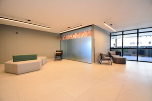 Eine moderne Lobby mit Sitzgelegenheiten, einem Empfangstresen und großen Fenstern mit Blick nach außen.