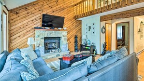 A living room with a stone fireplace, a television mounted above it, and a large grey sofa. - Walk to Locust Lake - Poconos Home w Fire Pit! (Pocono Lake)