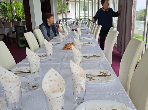 A long dining table with white tablecloths and floral napkins, set for a meal.