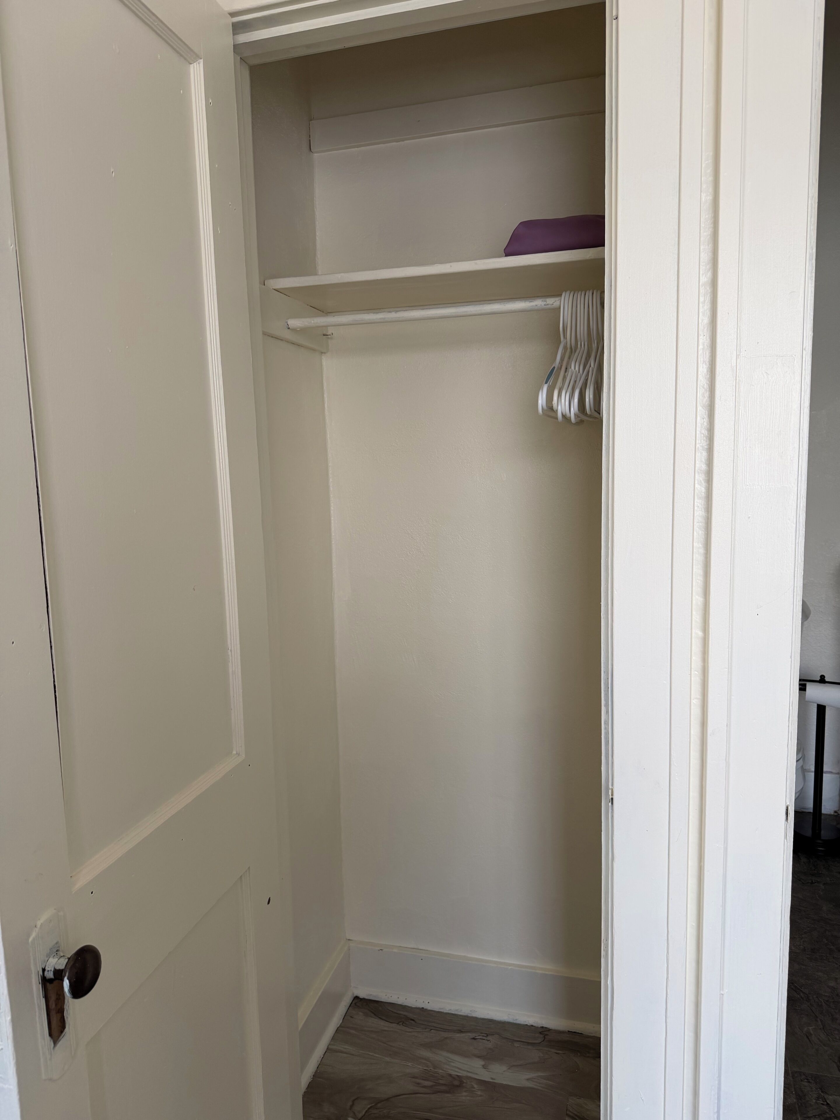 A white closet with a hanging rod and a shelf.