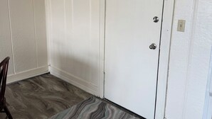 Een kamer met een witte deur, een houten vloer en een gestreept vloerkleed.