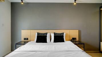 A modern hotel room with a large bed, two bedside tables, and a headboard.
