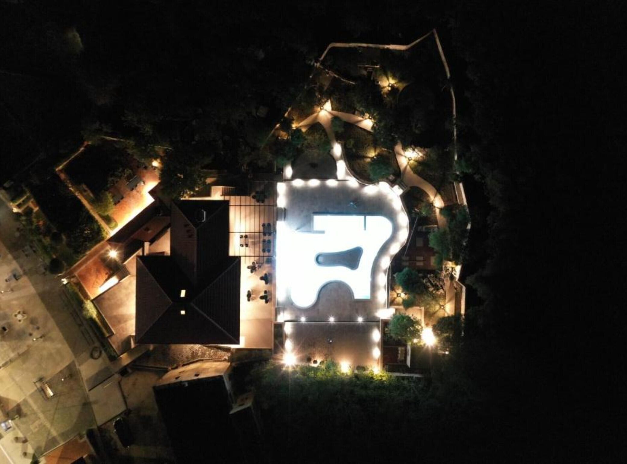 Vista aérea de un edificio moderno con un gran letrero iluminado con el número '5', rodeado de jardines ajardinados y zonas de estar al aire libre.