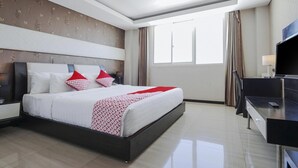 A hotel room with a bed, a desk, a TV, and a window with curtains. - Cozy Standard Double w/ City View & Free WiFi (Bali)