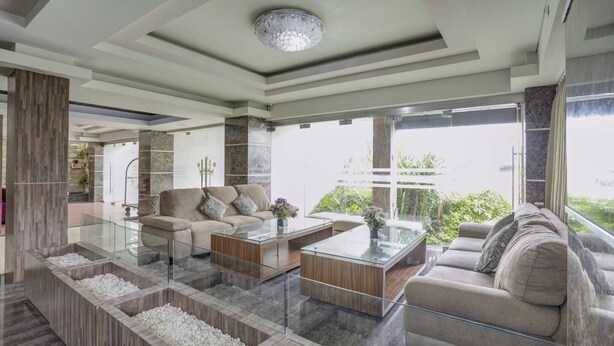 A modern living room with a glass coffee table, beige sofas, and a view of greenery outside. - Cozy Standard Double w/ City View & Free WiFi (Bali)