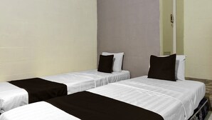 Een kamer met twee eenpersoonsbedden, elk voorzien van een witte matras en een zwart dekbed.