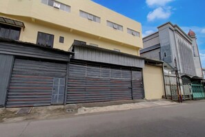 A building with closed metal shutters, a yellow facade, and a red dome on a taller structure.
