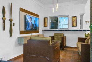 Una sala de estar con televisor, dos sillones, un sofá y una ventana con vistas.