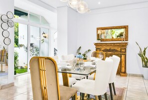 Un comedor con una mesa de vidrio, sillas blancas y una chimenea de madera.