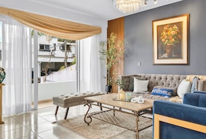 Ein Wohnzimmer mit Sofa, Couchtisch, Topfpflanze und einem gerahmten Bild an der Wand.