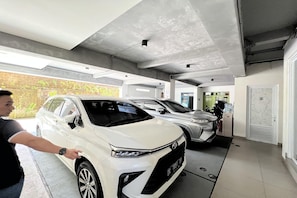 Un parking avec des voitures et une personne qui désigne une voiture blanche.