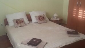 Ein Schlafzimmer mit einem Bett, Kissen, einem Nachttisch, einer Lampe und einem Kleiderschrank.